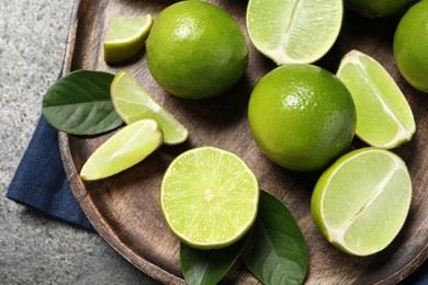 Fresh ripe limes and leaves on grey table, top view