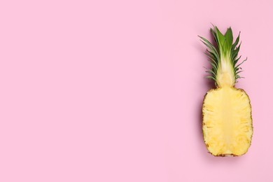 Half of ripe pineapple on pale pink background, top view. Space for text