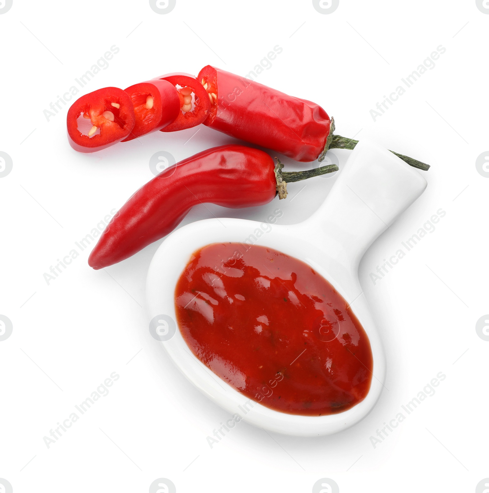 Photo of Dish with spicy chili sauce and fresh peppers on white background, top view