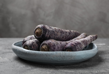 Photo of Fresh raw black carrots on grey table