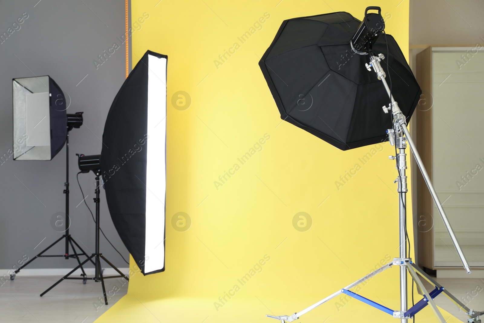 Photo of Yellow photo background and professional lighting equipment in modern studio