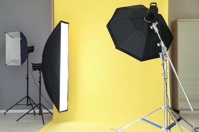 Photo of Yellow photo background and professional lighting equipment in modern studio