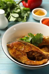 Photo of Tasty fish curry and ingredients on light blue wooden table, closeup. Indian cuisine
