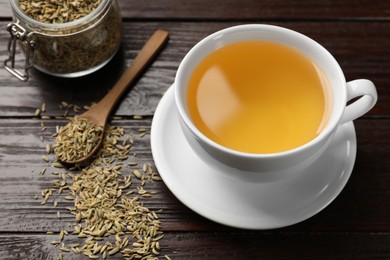 Photo of Fennel tea in cup and seeds on wooden table, closeup