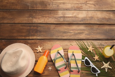 Beach accessories on wooden background, flat lay. Space for text