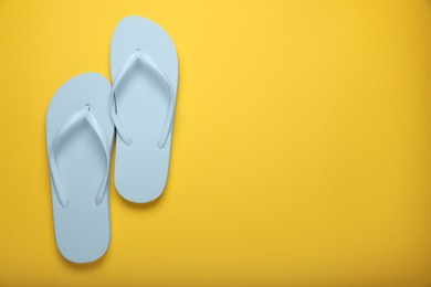 Photo of Stylish white flip flops on yellow background, top view. Space for text