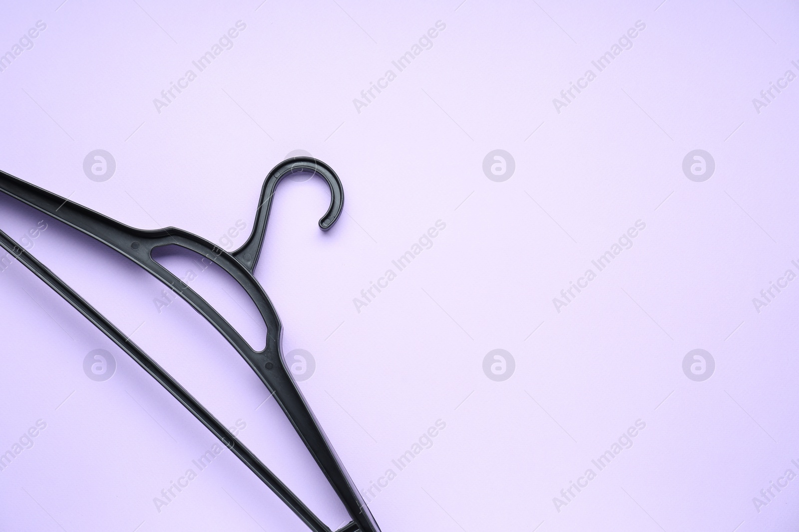 Photo of Empty black hanger on lilac background, top view. Space for text