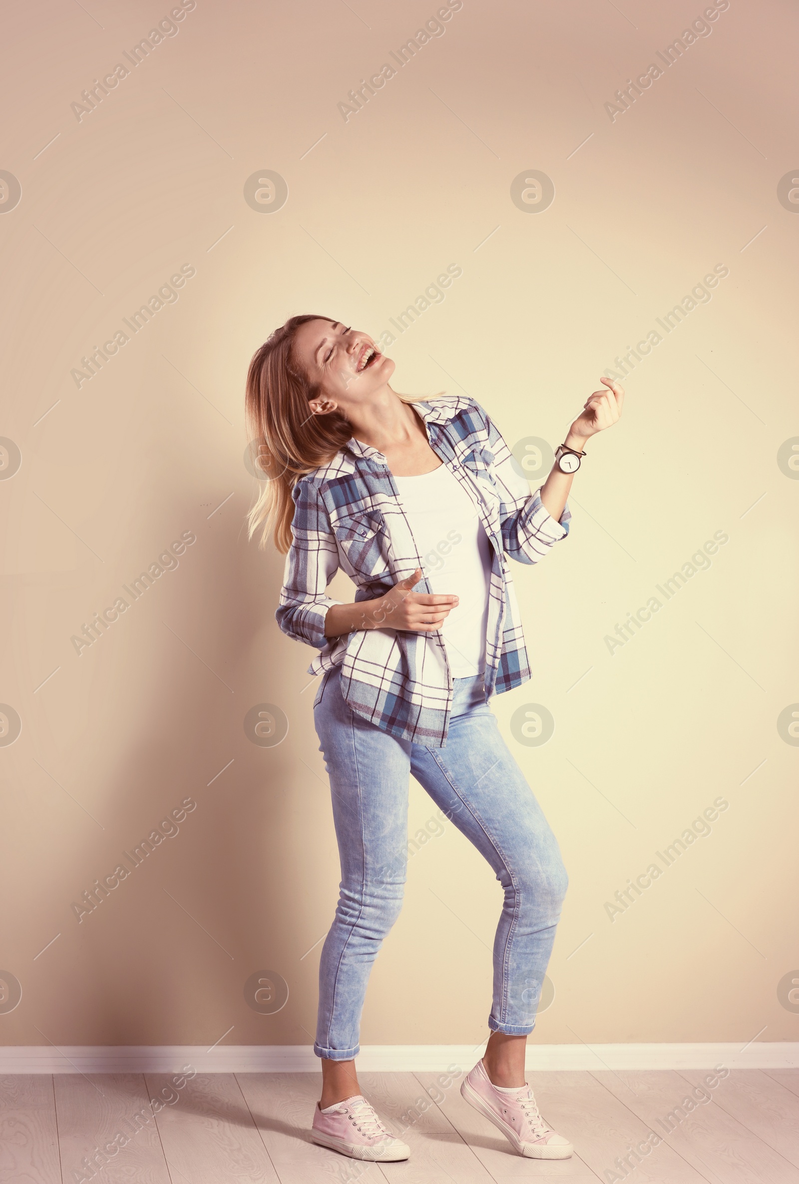 Photo of Young woman playing air guitar near grey wall