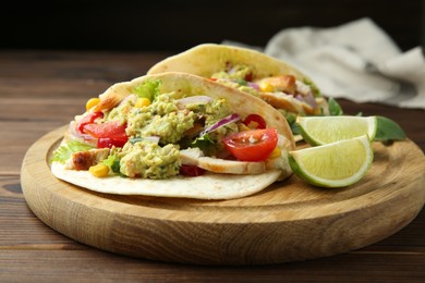 Photo of Delicious tacos with guacamole, meat and vegetables served with lime on wooden table, closeup