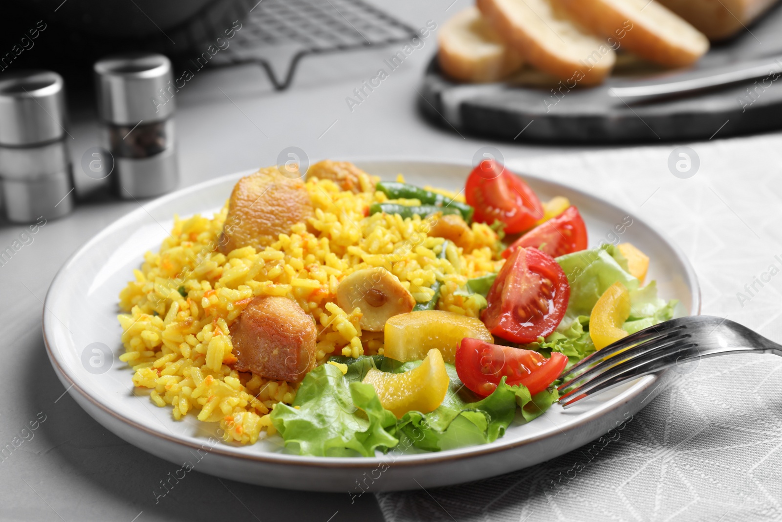 Photo of Delicious pilaf with chicken meat on light grey table