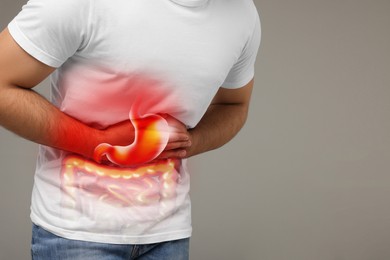 Image of Man suffering from stomach ache on grey background, closeup and space for text. Illustration of unhealthy gastrointestinal tract