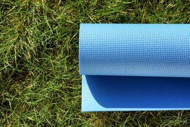 Photo of Bright exercise mat on fresh green grass outdoors, top view