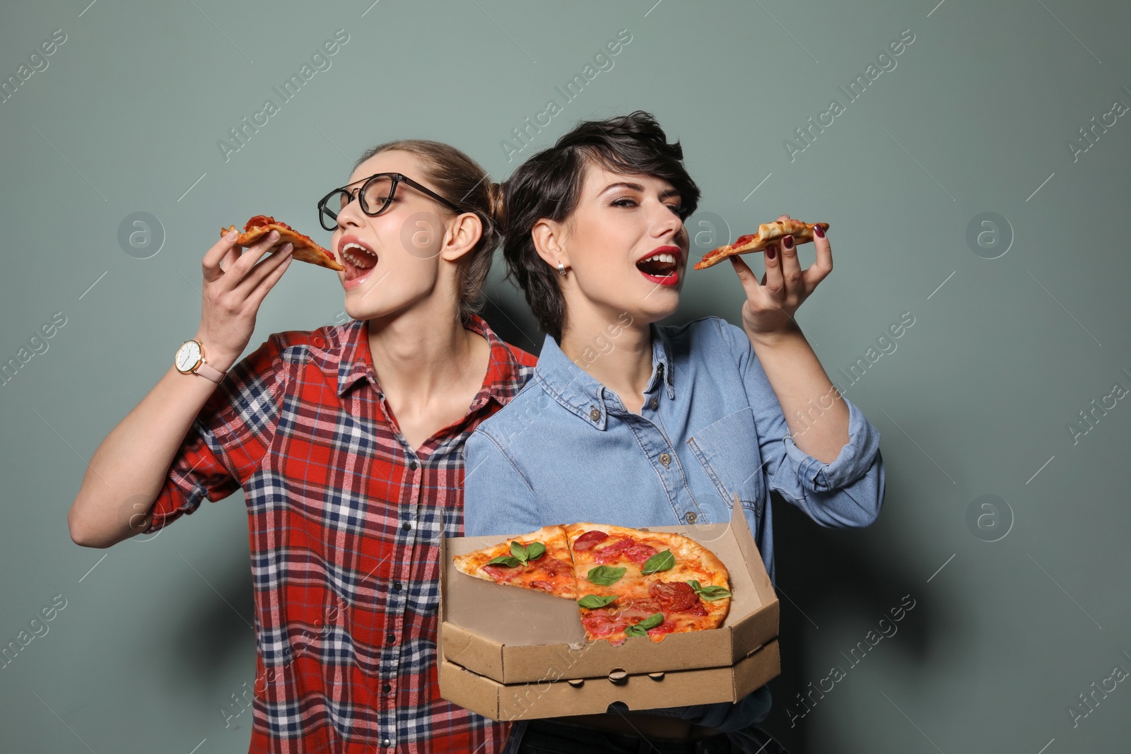 Photo of Attractive young women with delicious pizza on color background