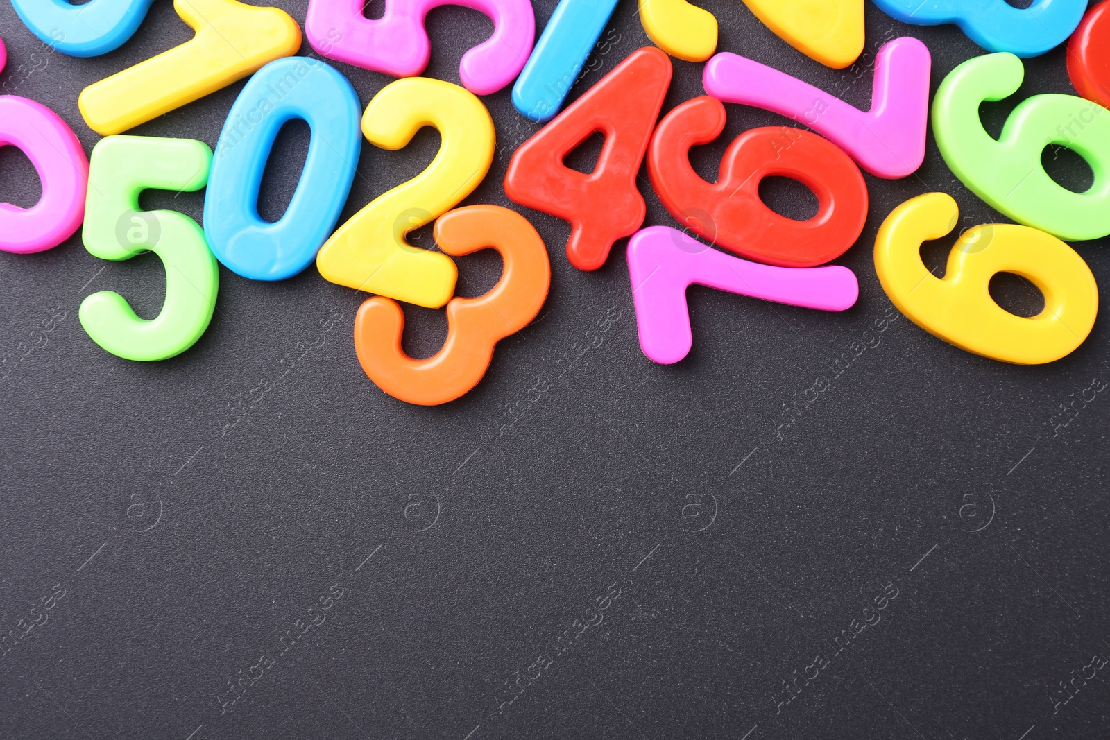 Photo of Colorful numbers on dark gray background, flat lay. Space for text