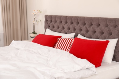 Photo of Double bed with bright pillows in room. Interior design element
