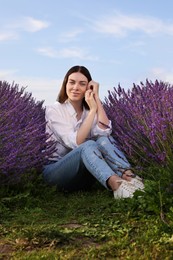 Photo of Beautiful woman sitting among lavender plants outdoors