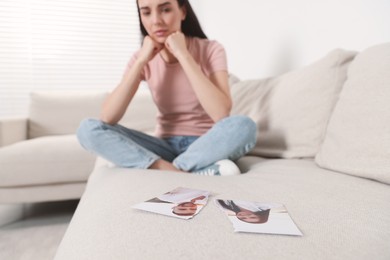 Photo of Upset woman looking at parts of torn photo in room, selective focus. Divorce concept