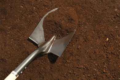 Photo of Metal shovel on fertile soil, space for text. Gardening tool