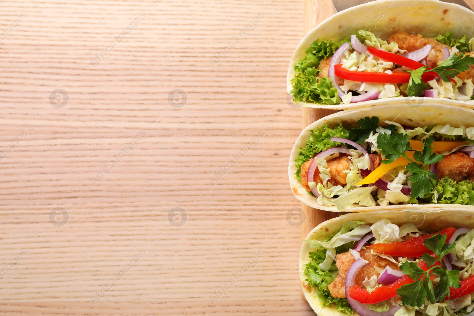 Photo of Delicious fish tacos served on wooden table, top view with space for text