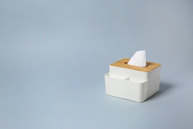 Holder with paper tissues on light grey background. Space for text