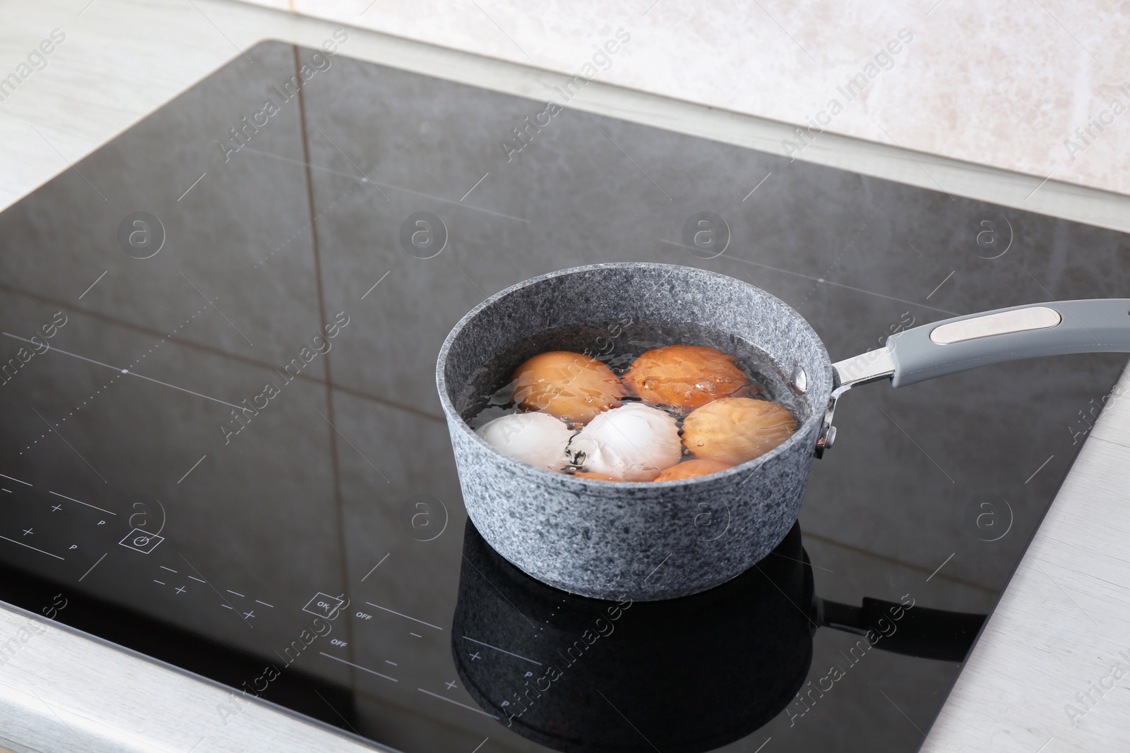 Photo of Chicken eggs boiling in saucepan on electric stove. Space for text