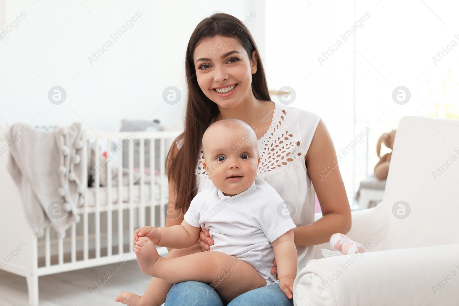 Photo of Young mother with her cute baby girl in armchair at home