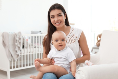 Photo of Young mother with her cute baby girl in armchair at home