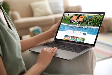 Image of Woman using laptop to book hotel at home, closeup