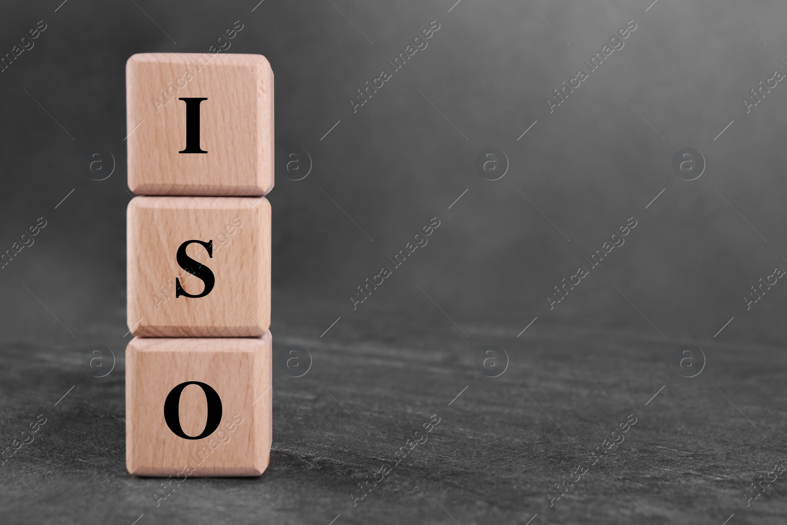 Photo of International Organization for Standardization. Cubes with abbreviation ISO on gray textured table, space for text