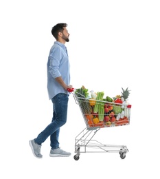 Young man with shopping cart full of groceries on white background