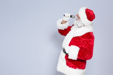 Photo of Santa Claus singing into microphone on color background. Christmas music