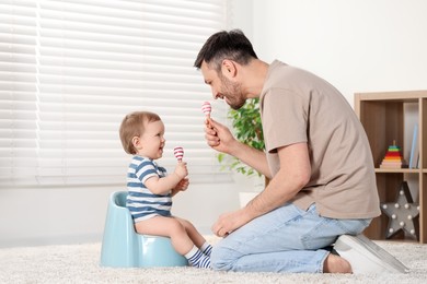 Photo of Father training his child to sit on baby potty indoors