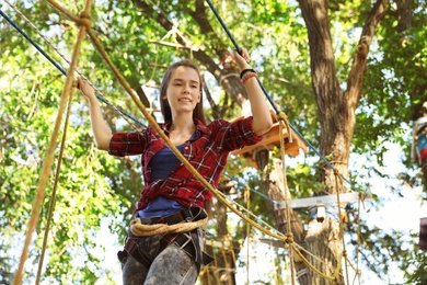 Teenage girl climbing in adventure park. Summer camp