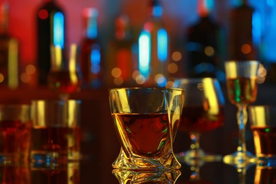 One liqueur in glass on mirror table in bar, closeup