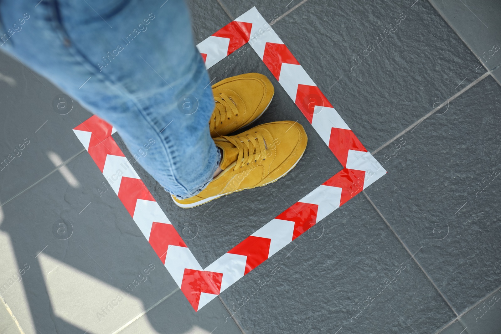Photo of Woman standing on taped floor marking for social distance, closeup. Coronavirus pandemic