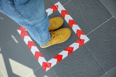 Woman standing on taped floor marking for social distance, closeup. Coronavirus pandemic