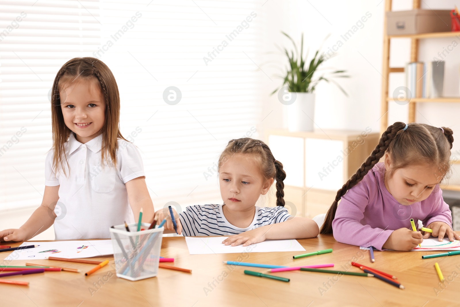 Photo of Cute little children drawing at wooden table indoors