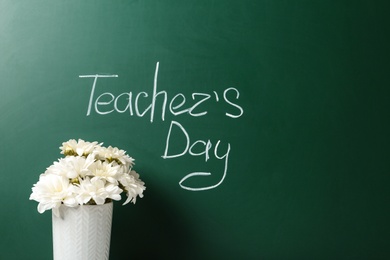 Photo of Vase of flowers near green chalkboard with inscription TEACHER'S DAY. Space for text
