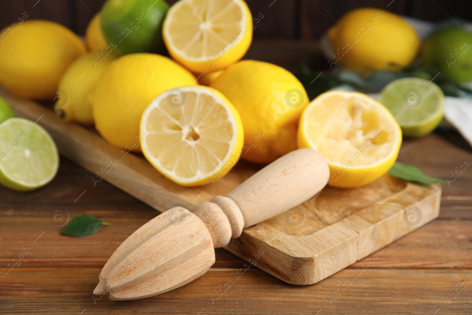 Photo of Squeezer with lemons on wooden table, closeup