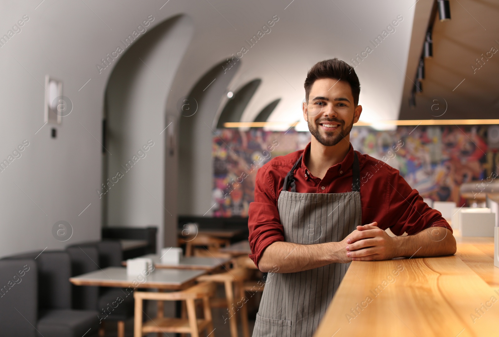Photo of Young male business owner standing near counter in his cafe. Space for text