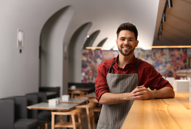 Photo of Young male business owner standing near counter in his cafe. Space for text