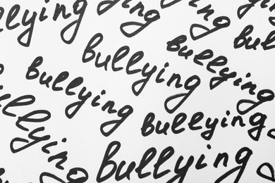 Photo of Top view of words Bullying written on white background, closeup
