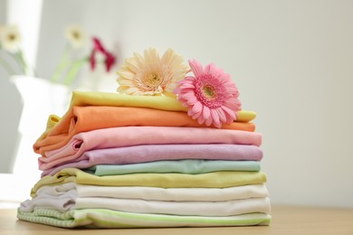 Stack of clean clothes and flowers on table