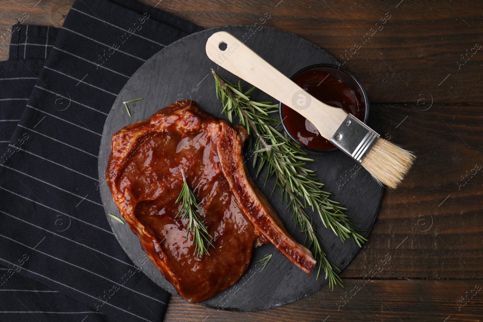 Photo of Tasty meat, rosemary, marinade and basting brush on wooden table, top view