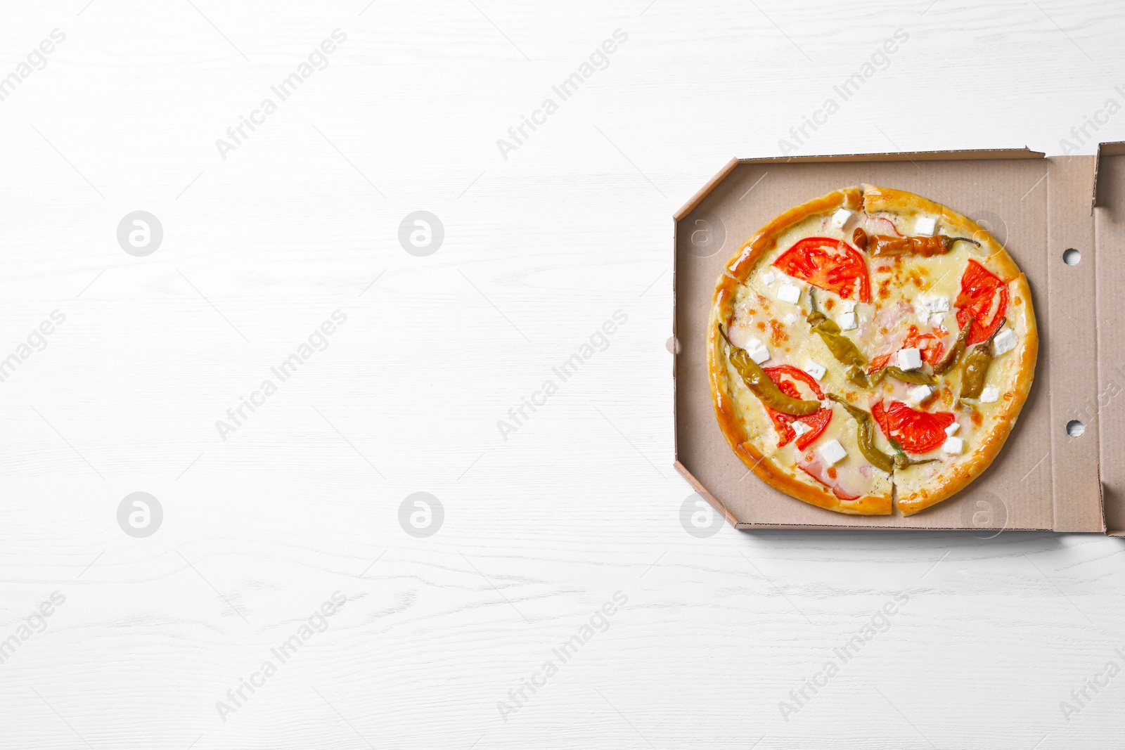 Photo of Cardboard box with tasty pizza on wooden background, top view with space for text