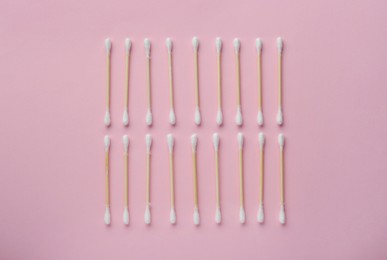 Many wooden cotton buds on pink background, flat lay