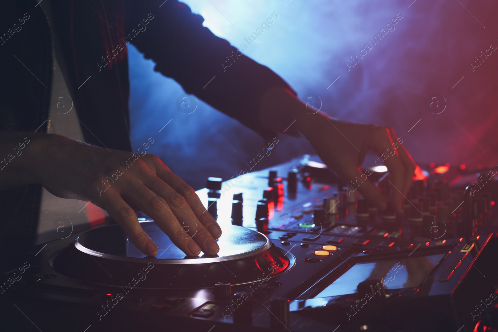 Photo of DJ creating music on modern console mixer in night club, closeup