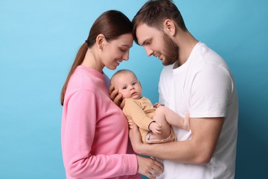 Photo of Happy family. Parents with their cute baby on light blue background