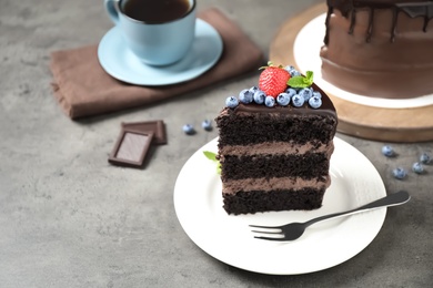 Photo of Piece of delicious chocolate cake decorated with fresh berries on grey table