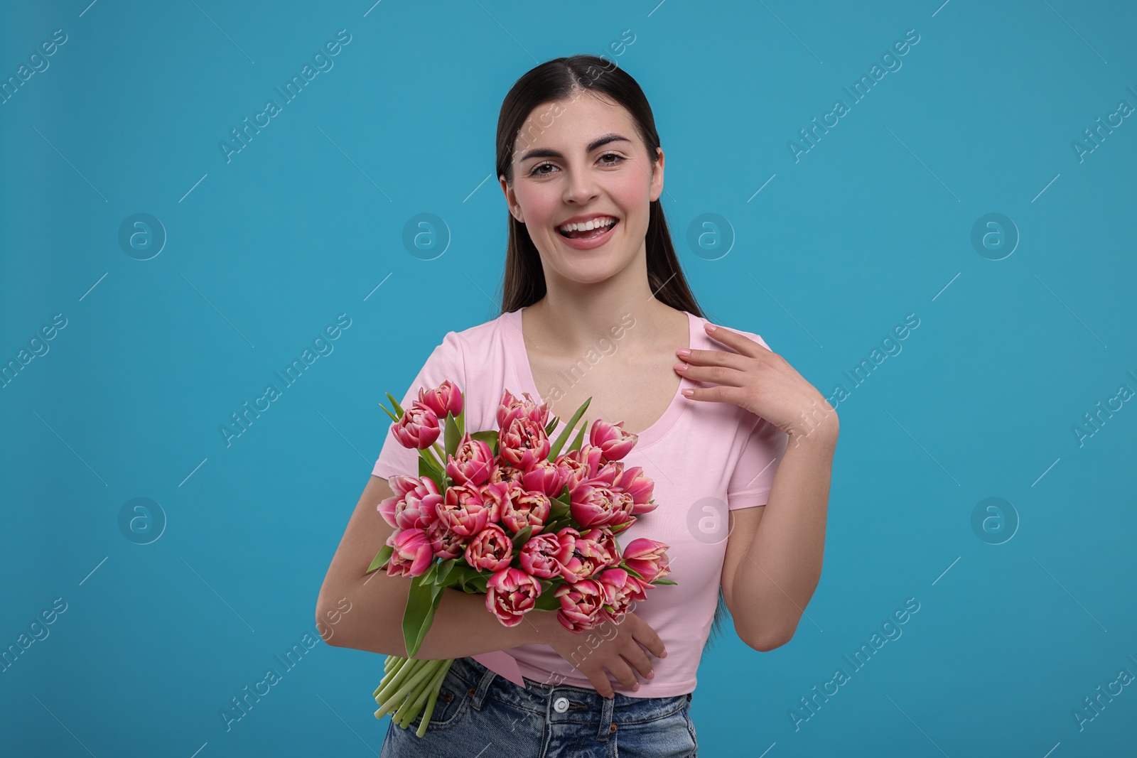 Photo of Happy young woman with beautiful bouquet on light blue background